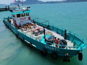 blue fuel barge showing tanks of fuel on deck, hoses and workers