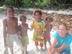 local children of varying ages from 8 to 4 dressed in colourful shorts and one with a bright t shirt with a crew member dressed in blue